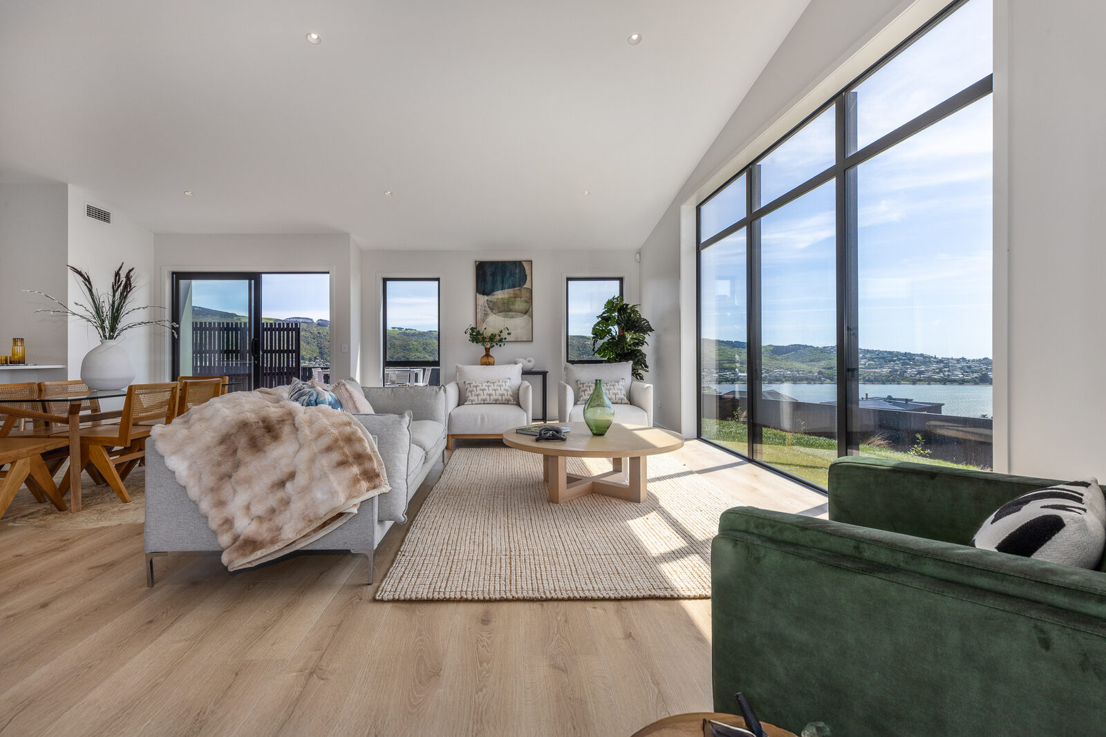 Open-plan living room with green sofa and harbour views