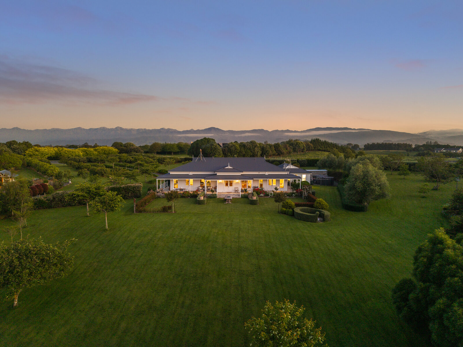 Aerial at dusk, country home set in green farmland